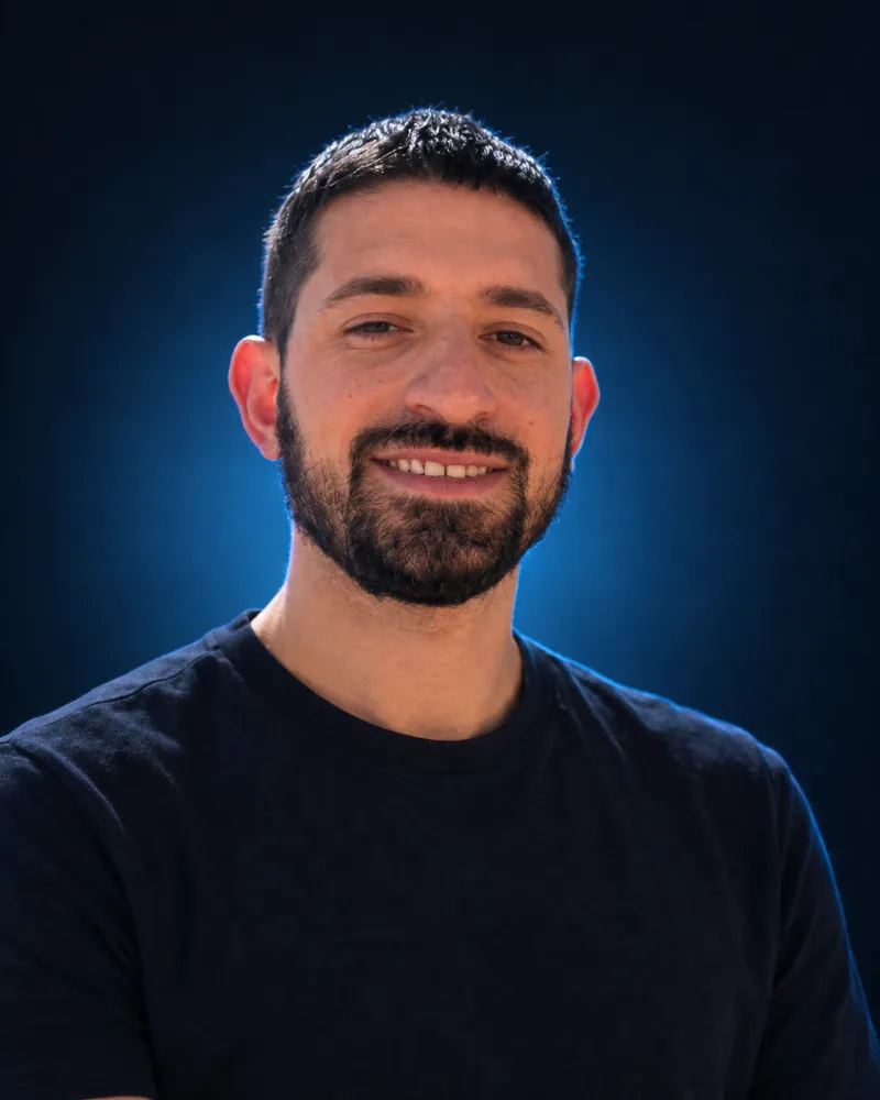 Foto de Benjamín Boyadjian, a cargo de producción y configuración en Lucca Cañada Studio, sonriendo frente a un fondo azul oscuro