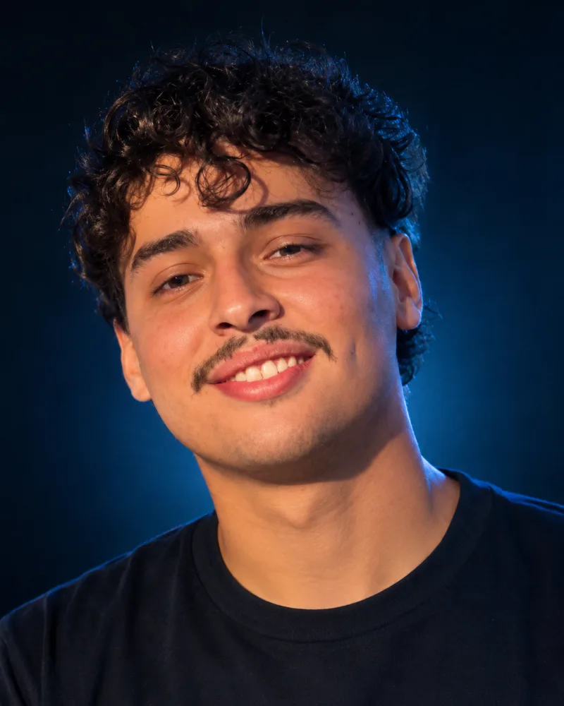 Foto de Lucca Cañada, fundador de Lucca Cañada Studio, sonriendo frente a un fondo azul oscuro